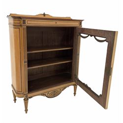 Late 19th century Regency design satinwood glazed cabinet the raised and floral carved back over rosewood cross banded top, frieze drawer with further rosewood banding, the glazed door with applied swags enclosing two adjustable shelves, shaped apron under with incised carving, raised on turned tapered and fluted supports 