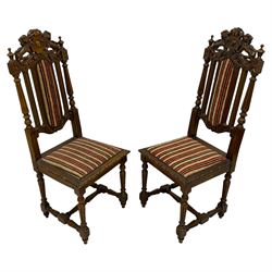 Pair of late Victorian Jacobean Revival heavily carved oak hall chairs, lion and cartouche cresting rail over fluted and slat back, striped upholstery, raised on turned fluted supports united by H-stretcher