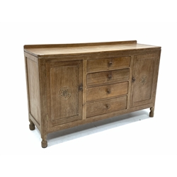 Wilf 'Squirrelman' Hutchinson of Husthwaite - Yorkshire oak sideboard, raised on over rectangular top with canted corners, bank of four graduated drawers flanked by two fielded cupboards carved with Yorkshire rose roundels, each enclosing a shelf, raised on octagonal turned supports 