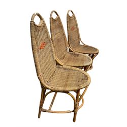 Set of three mid century wicker chairs raised on bamboo supports 