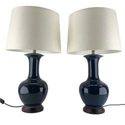 Pair of Chinese teal glazed table lamps, each of bottle form, raised upon circular hardwood bases, H72cm including shade