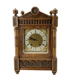 Lenzkirch - late 19th century German 8-day walnut mantle clock, with a gable pediment and carved decoration, turned finials and side frets, with a brass dial, cast spandrels, matted dial centre and a silvered chapter ring, twin train movement with a ting tang quarterly strike on two coiled gongs. With pendulum.