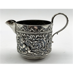 George III silver fiddle pattern sauce ladle London 1819, George IV sauce ladle London 1823 both by Thomas Wilkes Barker, pair of silver gilt serviette rings Birmingham 1957 and an embossed silver cream jug Chester 1902 7.7oz