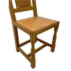 Knightman - set of four oak dining chairs, fielded panelled back over seat upholstered in tan leather with stud work, on octagonal front supports united by stretchers, by Horace Knight, Balk, Thirsk 