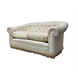 Pair chesterfield design two seat sofas, upholstered in buttoned cream fabric with butterfly pattern, fringe to base, on casters 