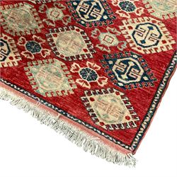 Persian crimson ground rug, the field decorated with all-over ivory and indigo geometric lozenges, enclosed by a narrow blue band