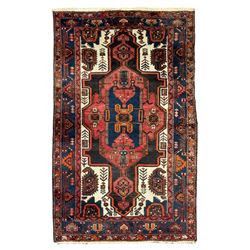 Persian Hamadan red ground rug, the field decorated with stylised plant motifs and geometric designs, the ivory spandrels with large Boteh motifs, the guarded indigo border with repeating geometric and bird motifs