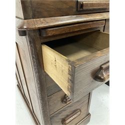 20th century oak roll top desk, the roll top opening to reveal fitted interior with pigeon holes and drawers, over one long and eight short drawers, raised on recessed castors  