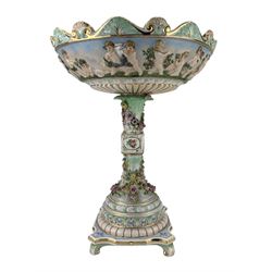 Dresden porcelain centrepiece, the bowl relief decorated with a continuous scene of Cherubs in a garden, the naturalistic stem encrusted with flowers, on four scroll supports, H41cm 