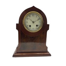 An Edwardian c1910 mahogany veneered mantle clock in a pointed arch case with inlaid satinwood stringing, white enamel dial with Arabic numerals and minute track,  matching steel moon hands within a cast bezel and convex glass, eight-day twin train French movement striking the hours and half hours on a coiled gong. With pendulum. 

