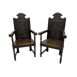 Pair of late 19th/ Early 20th century oak Wainscot chairs, the arched crest rail over floral and lunette carved panel back, out swept open arms, raised on turned front supports W68cm