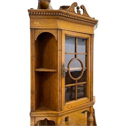 Late Victorian figured and pollard oak bow-front corner cabinet, the canted top section with dentil cornice over glazed door flanked by two shelves, turned supports and mirrored back with flower head carved triangular brackets, the bow-front lower section enclosed by two panelled doors carved with bulrush and foliate, on turned supports joined by undertier with square column gallery 