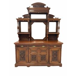Large Edwardian walnut mirror back sideboard, the arched and shaped pediment relief carved with scrolled acanthus leaf, sectional bevel glazed back with shelves and turned supports, the base fitted with three shelves, central double cupboard and two single cupboards, the front heavily carved with fruit urns and foliage, shaped skirted base