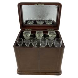 Edwardian mahogany decanter box, the mahogany banding strung with ebony, the hinged cover with internal mirror inset, set over two hinged doors enclosing a  fitted interior with three later glass decanters and drinking glasses and single drawer fitted to base, H33.5cm, W35cm, D25cm