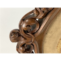 Victorian walnut fire screen, the cartouche shaped frame enclosing needlework panel depicting the Deramore family crest of Heslington Hall, surmounted by pierced and carved acanthus leaf and floral pediment, further floral decoration carved in relief to the four scrolled and splayed supports, upon brass castors 