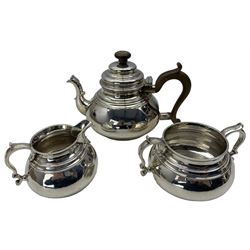 Silver three piece tea set of compressed circular form, the teapot with stained handle and lift and capped spout London 1933 Maker William Comyns and Sons Ltd
