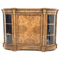 Victorian figured walnut credenza sideboard, the top with gilt metal beading to the edge over floral inlaid frieze and panelled door to centre enclosing two shelves and a draw, flanked by columns with gilt metal leaf moulded capitals and two glazed doors, each enclosing two shelves, W154cm, H106cm, D42cm.
