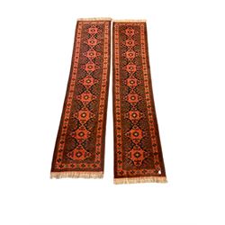 Pair of Persian runner rugs of geometric design on red field with floral border and twin guard stripes 