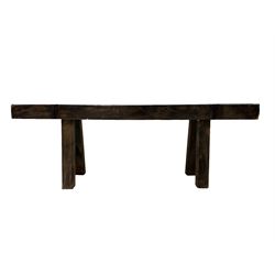 African Carved hardwood bench, the top carved with a spiral border flanked by stylised masks, raised on splayed supports