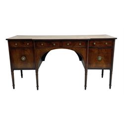 George III figured mahogany breakfront sideboard, the moulded top over five drawers and wide arched aperture, inlaid with satinwood and ebony stringing, foliate decorated brass plate handles, on turned supports