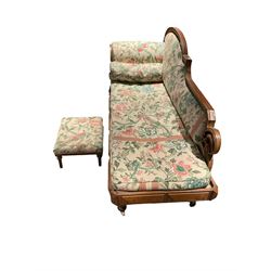 19th century oak chaise longue, shaped back with egg and dart carved edge with acanthus leaf scrolled roundel, scrolled back carved with trailing bell flower heads, upholstered in neutral ground fabric decorated with floral and bird pattern, the frieze rail with faceted panel mounts, turned and egg and dart carved feet with brass and ceramic castors, with footstool
