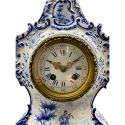 French Faience porcelain mantle clock with blue and white decoration c1890, in a rococo style case with scrollwork and floral decoration, the centre painted with a rural scene of a lady in 18th century costume, with a Parisian eight day rack striking movement stamped “Marti”, “medaille d' argent”, enamel dial with blue roman numerals, five minute Arabic's and minute track, gilt Louis XV style hands within a decorative cast bezel and plain slip with a flat bevelled glass, movement striking the hours and half-hours on a gong. With pendulum