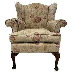 Late 20th century beech framed armchair, upholstered in floral pattern fabric with sprung seat, on cabriole front supports
