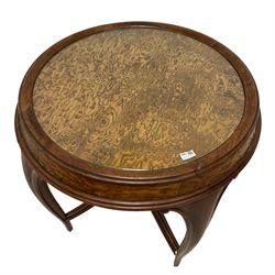 Late 19th century elm and walnut centre table, circular top with glass inset, on four cabriole supports with scroll carvings, joined by shaped and moulded stretchers with central flower head carved finial