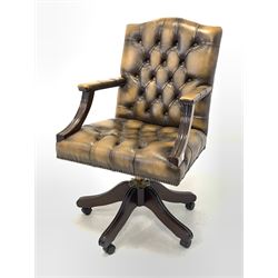 Antique design desk chair, upholstered in deep buttoned and studded tan leather, raised on swivel base with castors W61cm