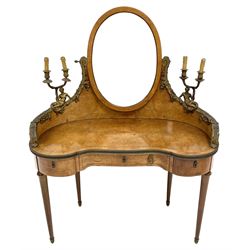 Late 19th century amboyna and ormolu mounted dressing table, the raised oval mirror with bevelled plate supported by sweeping raised back mounted with cast merfigures holding two branch sconces, decorated with scrolled leaf and floral festoons, kidney shaped form with satinwood band, fitted with three drawers, on turned tapering supports with gilt metal caps