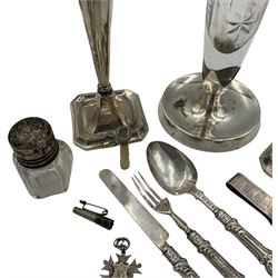 Indian engraved white metal beaker with applied silver shield shape cartouche H11cm, silver bladed three piece christening set, modern silver money clip, pair of silver candlesticks H18cm Birmingham 1919, glass and silver vase and other items