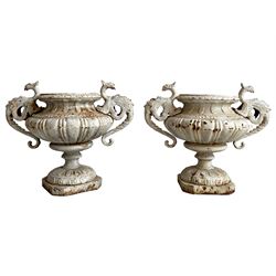 Pair of 19th century cast iron garden urns, shaped bowls mounted by Griffin shaped handles, on circular footed base moulded with stylised flower heads 