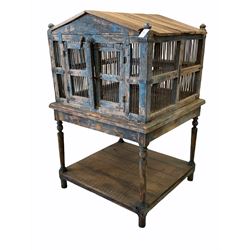Indian hardwood song birdcage on stand, the pitched roof over iron bound frame with double door and iron grills, raised on turned supports united by under tier 96cm x 93cm, H150cm