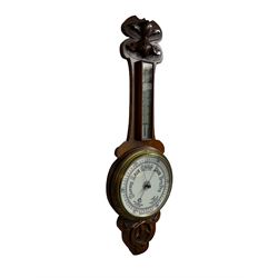 An oak cased aneroid barometer with carved relief c1930, with an 8” porcelain dial measuring atmospheric air pressure from 26 to 31.9 inches, weather predictions in Gothic and Roman script, with a brass indicating hand and steel recording hand within a brass bezel and flat glass, with a glazed thermometer box and mercury thermometer recording the temperature in degrees Celsius and Fahrenheit. 



