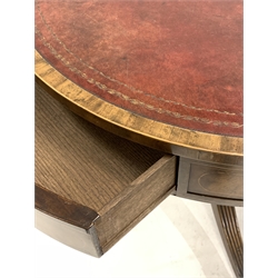 Regency style walnut drum table, with tooled red leather inset top over four drawers and four faux drawers, raised on turned column, three reeded splayed supports terminating in metal cup castors, D76cm, H69cm