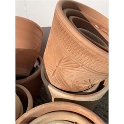 Twenty five circular terracotta plant pots, various sizes, some decorated with stars,