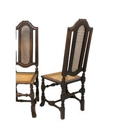 Set of four Victorian oak high back hall chairs of an earlier design, shaped crest rail over cane back and seat panel, raised on turned and block supports terminating in splayed and reeded carved feet 
