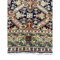 Azerbaijani ivory ground rug, the indigo field decorated with interconnecting divisions each enclosing geometric stylised plant motifs, the guarded border with repeating flower heads connected by foliage