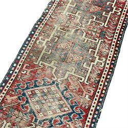 Antique Persian crimson ground runner rug, the field decorated with six central geometric medallions and lozenges, surrounded by stylised plant motifs, guarded indigo and ivory border