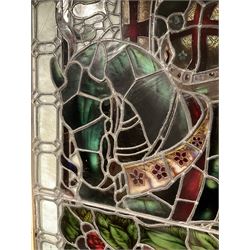 Late 19th century church stained and leaded glass window, the top inscription reading 'Through Labour to Rest, Through Combat to Victory', over a mounted crusader knight holding a lance and shield with the templar cross, the ribbon banner behind with three Lancastrian roses, the horse's and knight's breastplates both decorated with further roses, three heraldic crests to the base including the 'Worshipful Company of Fishmongers' with crossed keys over crowned fish, and a ship over a globe being a navigator symbol