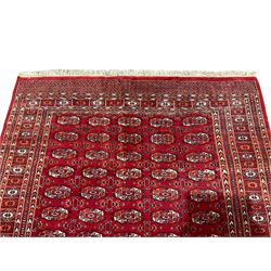 Persian Bokhara red ground rug, the field decorated with five columns of Gul motifs with surrounding geometric shapes, the symmetrical guarded border with repeating patterns in amber and ivory
