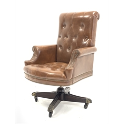 20th century captains swivel armchair, upholstered in deep buttoned studded brown leather, raised on reeded cruciform base with brass hairy paw terminals and casters, 