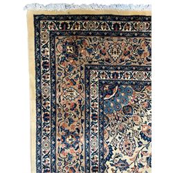 Persian ivory ground rug, central rosette medallion surrounded by stylised peony motifs and trailing leafy branches, the spandrels matching the medallion, repeating scrolling border with stylised plant motifs, within guard bands