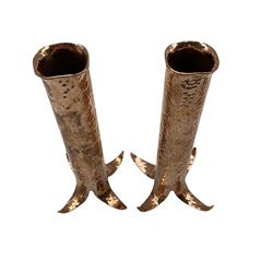 Pair of hammered copper cylindrical vases on splayed supports, H19.5cm 