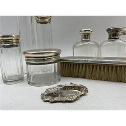 Silver mounted glass globe scent bottle Chester 1912, silver mounted glass match striker, seven glass dressing table jars with silver covers, modern silver decanter label and a silver backed brush (11)