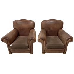 Pair of early 20th century club armchairs, traditional shape with rolled arms, upholstered in tan leather with loose seat cushion, on compressed bun feet with castors