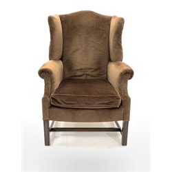 Georgian design wing back armchair, upholstered in brown velvet with loose cushion, raised on square moulded front supports united by stretcher, W75cm