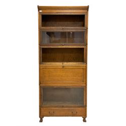 Early to mid-20th century five sectional stacking library bookcase, four sections with hinged sliding doors, one section with fall front enclosing fitted interior, and lower drawer to base, raised on carved paw feet