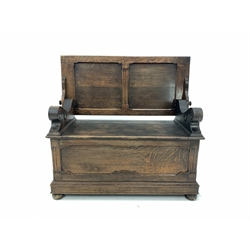Early 20th century oak monks bench, the folding panelled back rest over hinged seat, panelled front and sides, raised on bun supports 