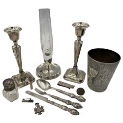 Indian engraved white metal beaker with applied silver shield shape cartouche H11cm, silver bladed three piece christening set, modern silver money clip, pair of silver candlesticks H18cm Birmingham 1919, glass and silver vase and other items